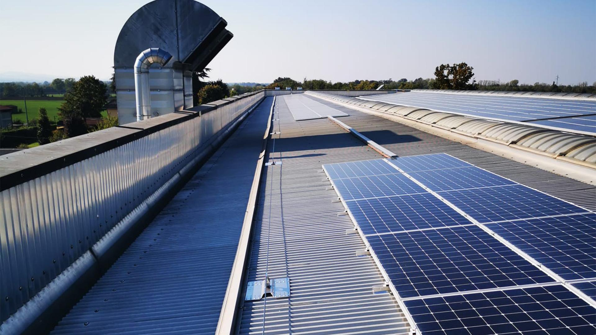Industrial metal roof with solar panels and fall protection lifeline system.