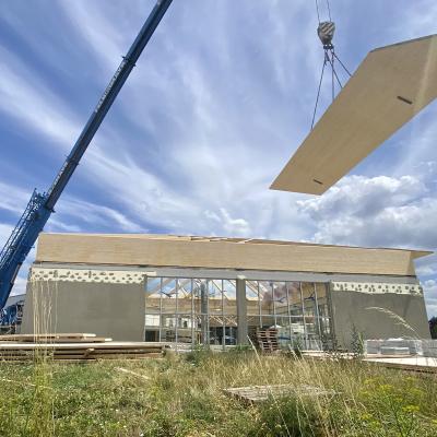 Crane lifting prefabricated timber roof panel on construction site using lifting systems for wooden prefabricated buildings