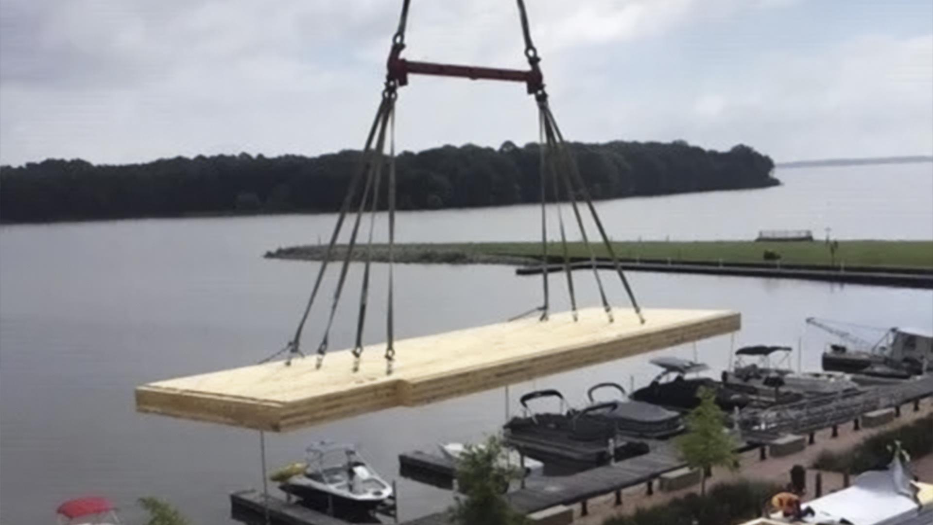 Crane lifting large prefabricated timber panel using multi-point lifting system on construction site for wooden prefabricated buildings 