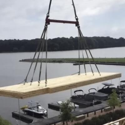 Crane lifting large prefabricated timber panel using multi-point lifting system on construction site for wooden prefabricated buildings