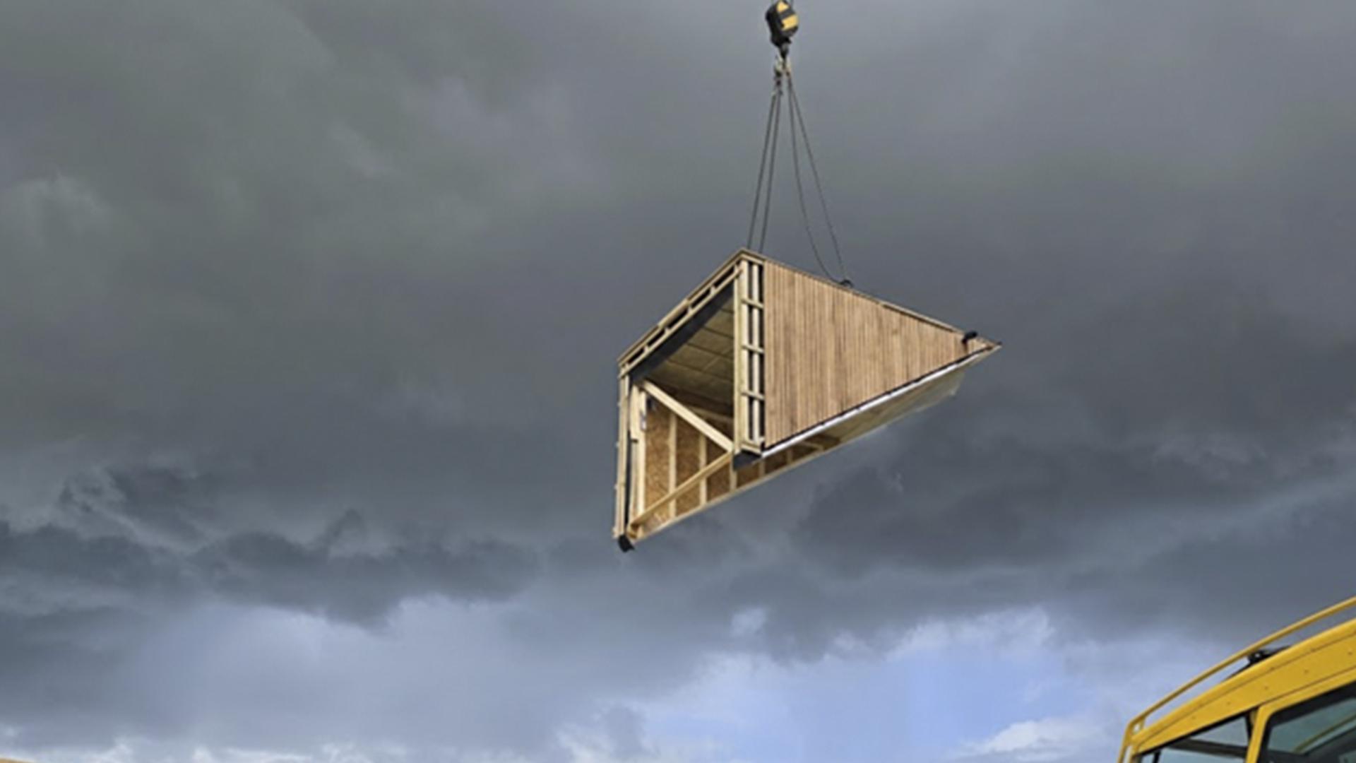 Crane lifting prefabricated timber room module on construction site using lifting equipment for wooden prefabricated buildings 