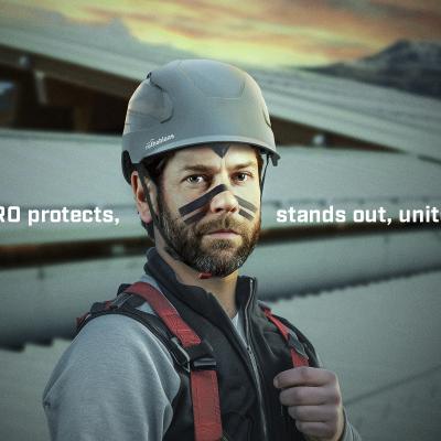 Worker wearing Rothoblaas HERO safety helmet in grey and a safety harness, in an industrial setting