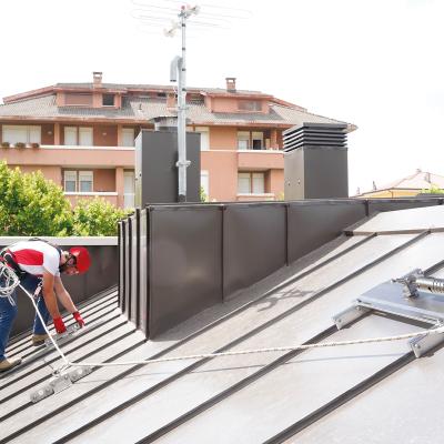 Permanent rail fall protection system installed on metal roof with worker connected to anchorage point for construction site safety 