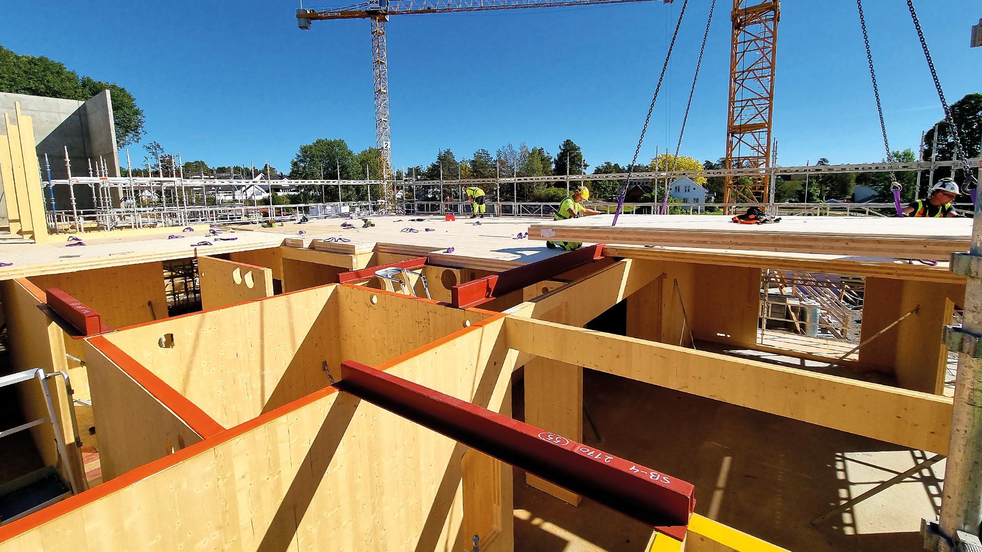 Mass timber construction site with CLT panels installation and workers assembling timber floor structure 