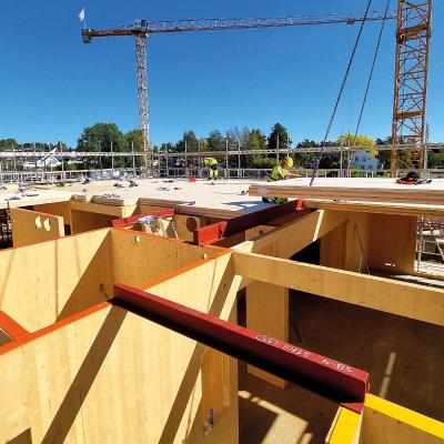 Mass timber construction site with CLT panels installation and workers assembling timber floor structure