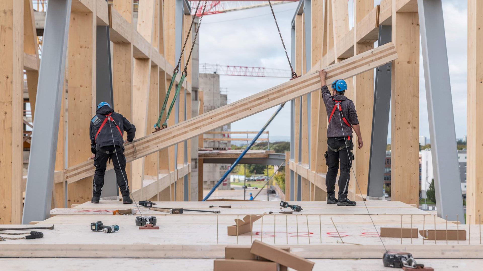 Mass timber construction site with workers installing structural timber elements in a sustainable building project 