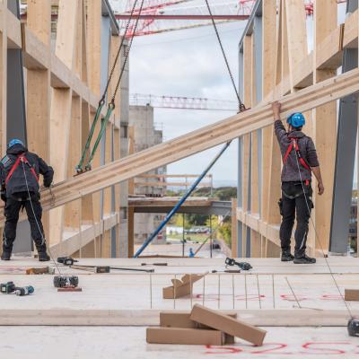 Mass timber construction site with workers installing structural timber elements in a sustainable building project 