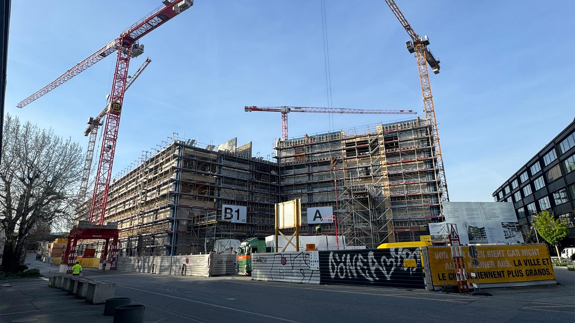 Large-scale construction site with cranes and multi-storey engineered timber building under assembly