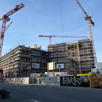 Large-scale construction site with cranes and multi-storey engineered timber building under assembly