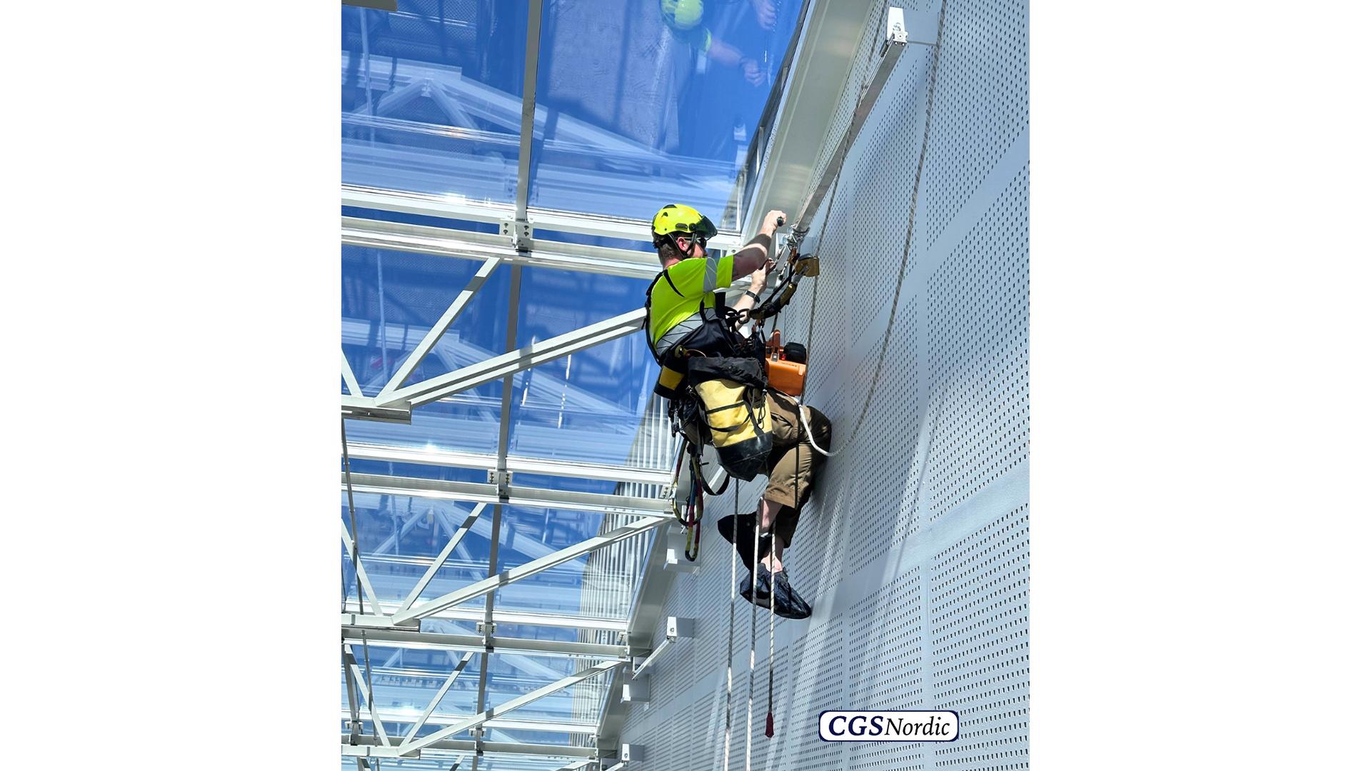H-RAIL rigid rail system mounted on steel structure under glazed atrium roof, installed by CGS Nordic to enable rope access for safe maintenance of atriums and glazed surfaces.
