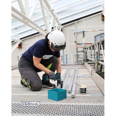 Rope access technician in safety harness suspended from H-RAIL system, working alongside the glazed wall of a building atrium for maintenance and inspection.