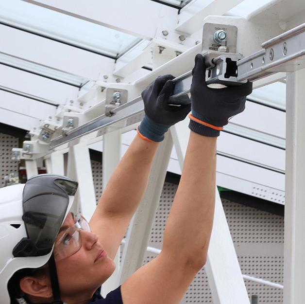 Interior view of a glazed building atrium with white steel roof trusses equipped with H-RAIL rope access system, installed by CGS Nordic for safe building maintenance.