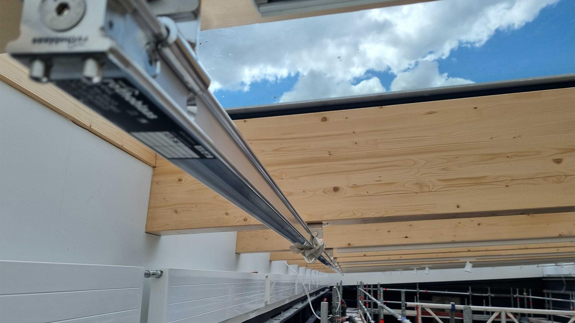  Rothoblaas H-RAIL horizontal lifeline system running along glulam timber beams of a large-span glazed timber roof during construction — Rebteknikeren ApS, Denmark.